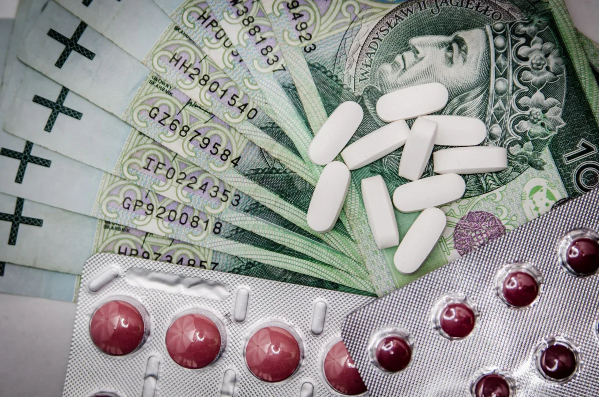 Polish 100 złoty notes with pills and blister packs, illustrating costs.