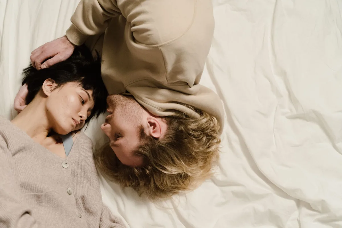 A loving couple lying together on a bed, symbolizing affection and relaxation.