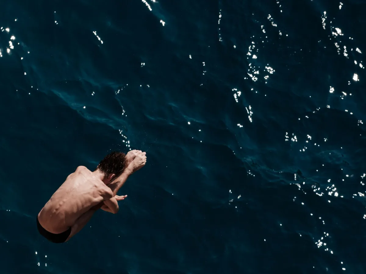 An adventurous diver gracefully plunges into the crystal-clear deep blue sea, embodying thrill and freedom. An adventurous diver gracefully plunges into the crystal-clear deep blue sea, embodying thrill and freedom.