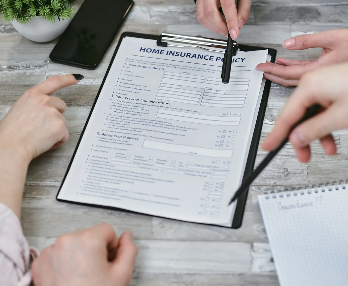 Three individuals collaborating on a home policy document. Elements include a clipboard, notes, and pointing hands.