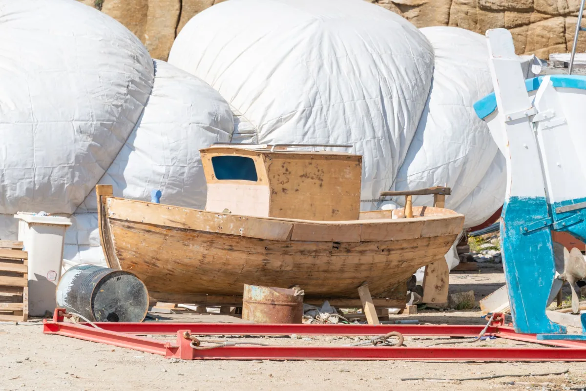 Wooden fishing alongside covered boats in a sunny harbor repair area. Wooden fishing alongside covered boats in a sunny harbor repair area.