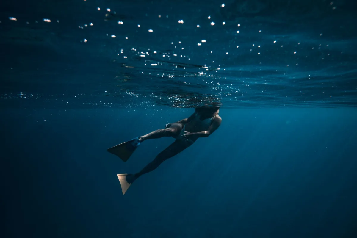 A breathtaking underwater shot of a freediver swimming in deep blue ocean waters. A breathtaking underwater shot of a freediver swimming in deep blue ocean waters.