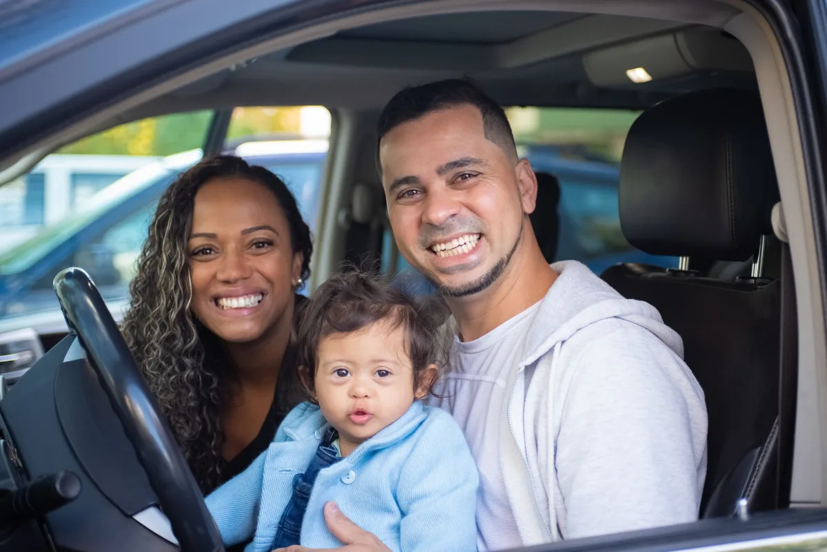 Family of three smiling in a car, showcasing joy and togetherness. Family of three smiling in a car, showcasing joy and togetherness.