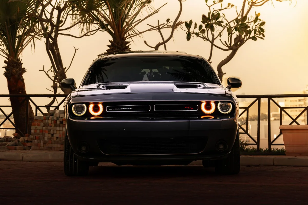 A sleek with illuminated headlights parked outdoors during sunset.