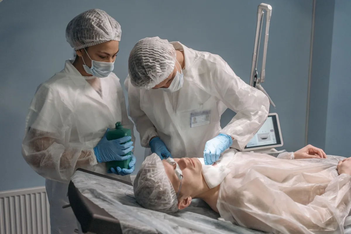 Surgeons in sterile gowns performing a procedure on a patient in an operating room setting.