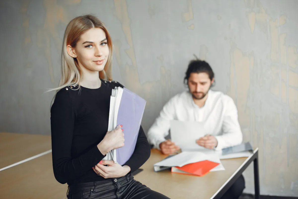 Young professionals in a modern office setting, holding documents and collaborating.